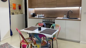 A modern kitchen with wooden cabinets, a built-in oven, a sink, and colorful chairs. - Studio 11 bis – Facing Vichy Parks (Vichy)