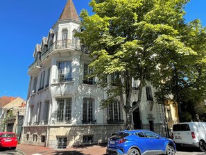 A historic building with a prominent tower, large windows, and a tree in front.