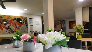 A dining area with a white table, three grey vases with flowers, and a mural on the wall. - HOTEL LA CASA No. 1 (Montería)