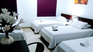 A hotel room with two single beds, a table with a vase of flowers, and a chair. - HOTEL LA CASA No. 1 (Montería)