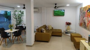 A modern living room with a sofa, a TV, and a dining area with chairs and a table. - HOTEL LA CASA No. 1 (Montería)