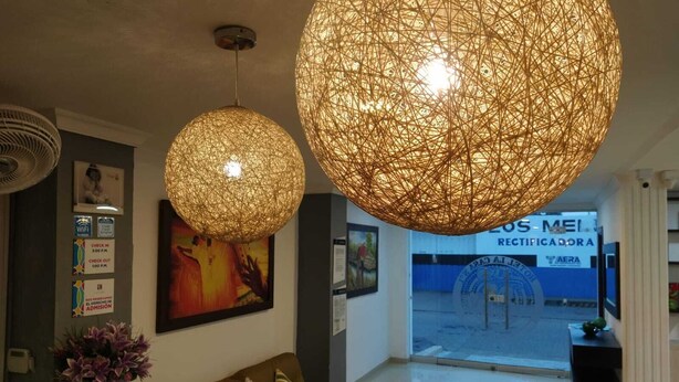 A reception area with a brown sofa, a TV, and two large spherical hanging lights. - HOTEL LA CASA No. 1 (Montería)