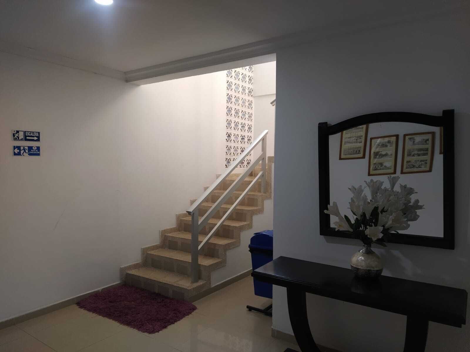 A staircase leading to a landing with a patterned wall, a blue trash bin, and a framed picture on the wall.