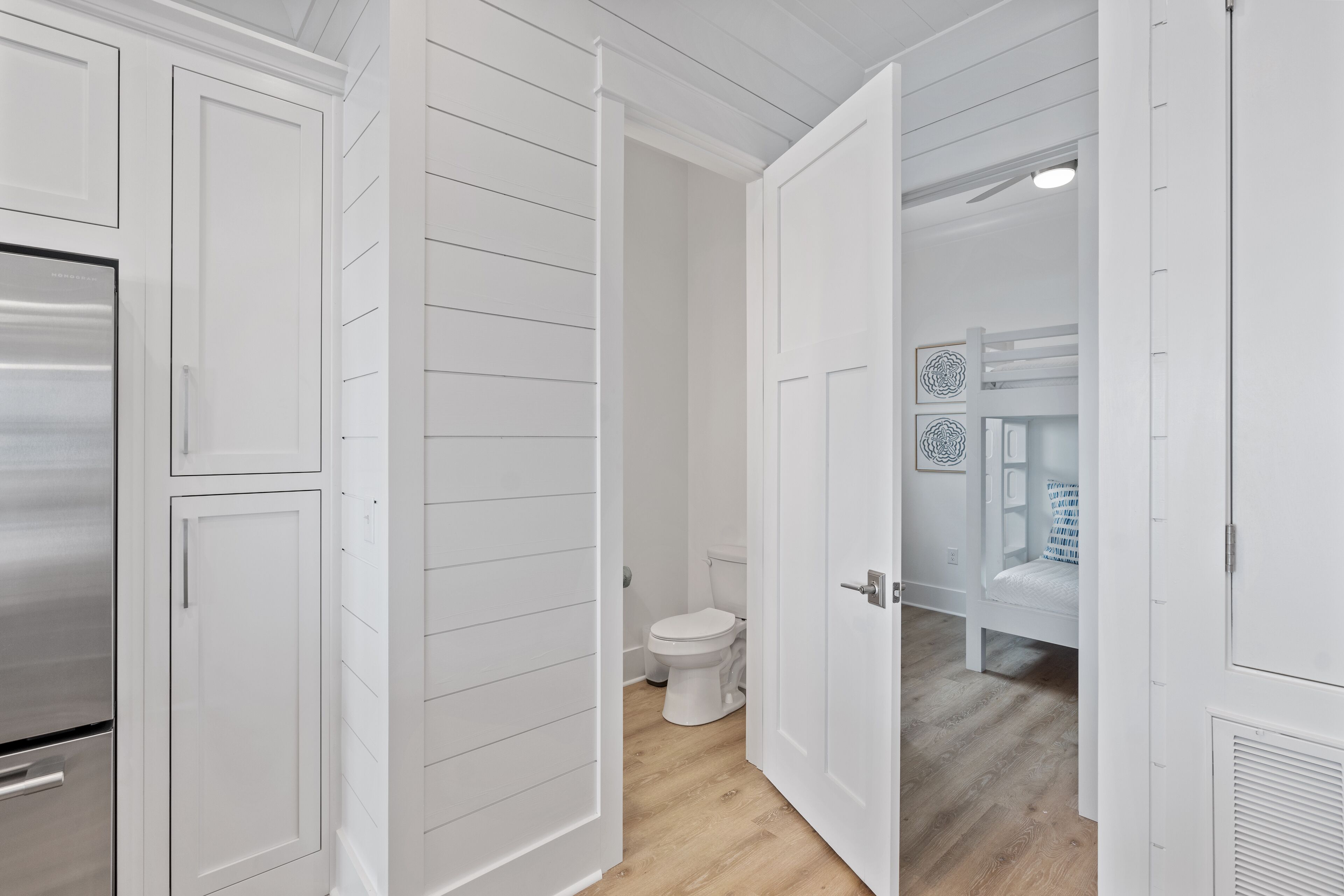 A hallway with white doors leading to a bathroom and a bedroom.