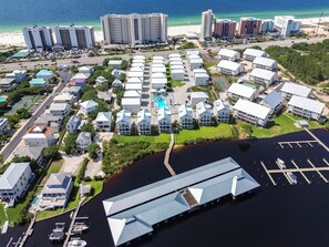 An aerial view of a coastal residential area with multiple buildings, a marina, and a beach in the background. - BRAND NEW HOME-Marlin Time-The Osprey-Signature Properties (Orange Beach)