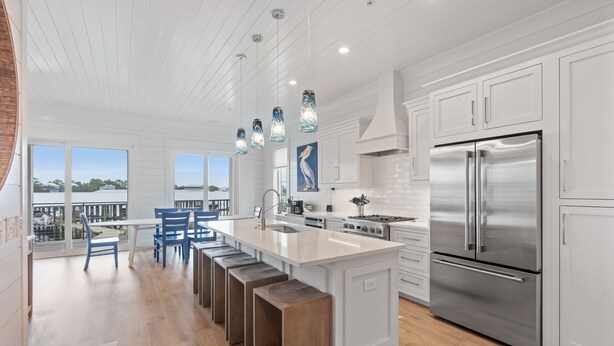 A modern kitchen with a large island, stainless steel appliances, and a view of the outdoors.