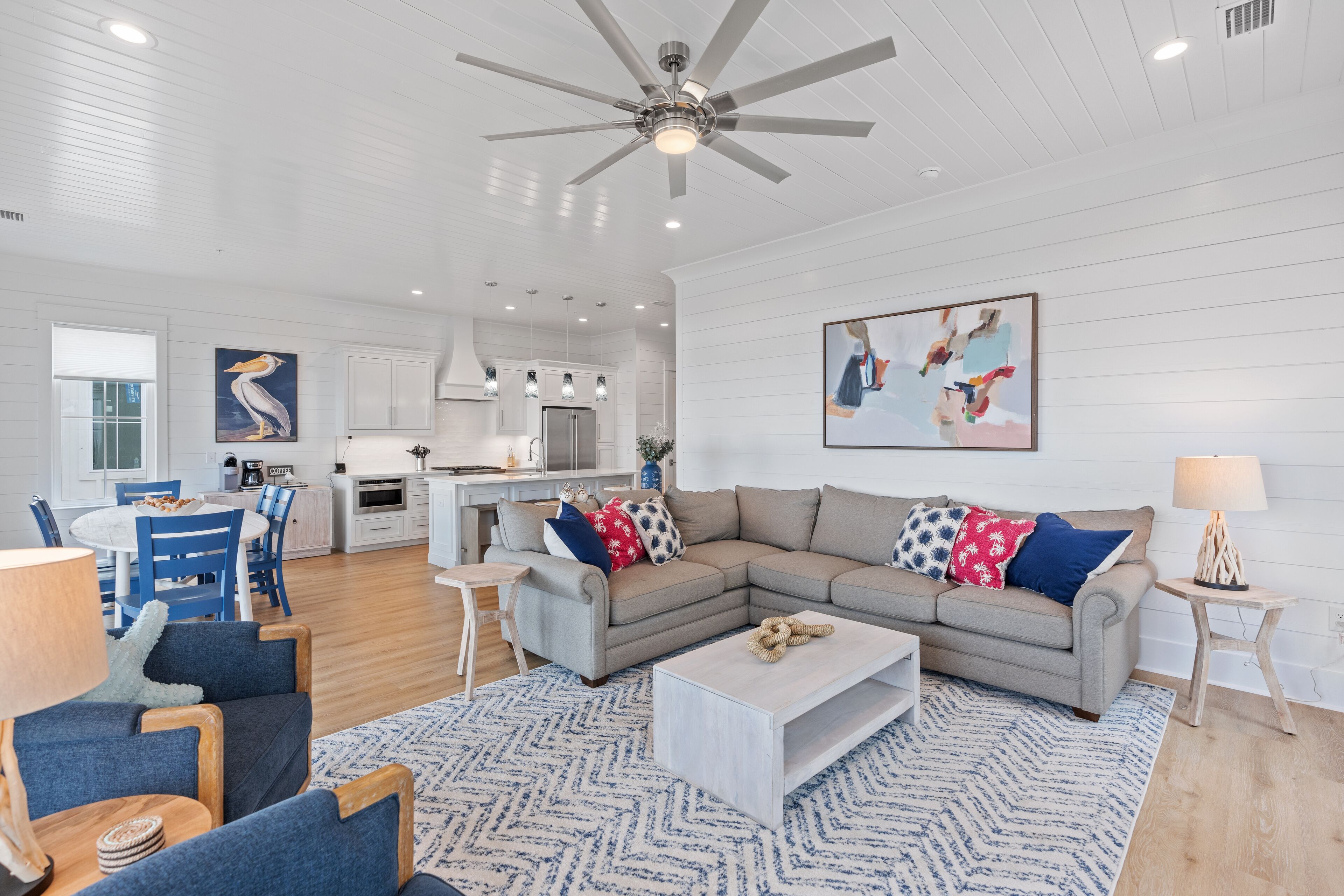 A modern living room with a sectional sofa, a coffee table, and a dining area with blue chairs.