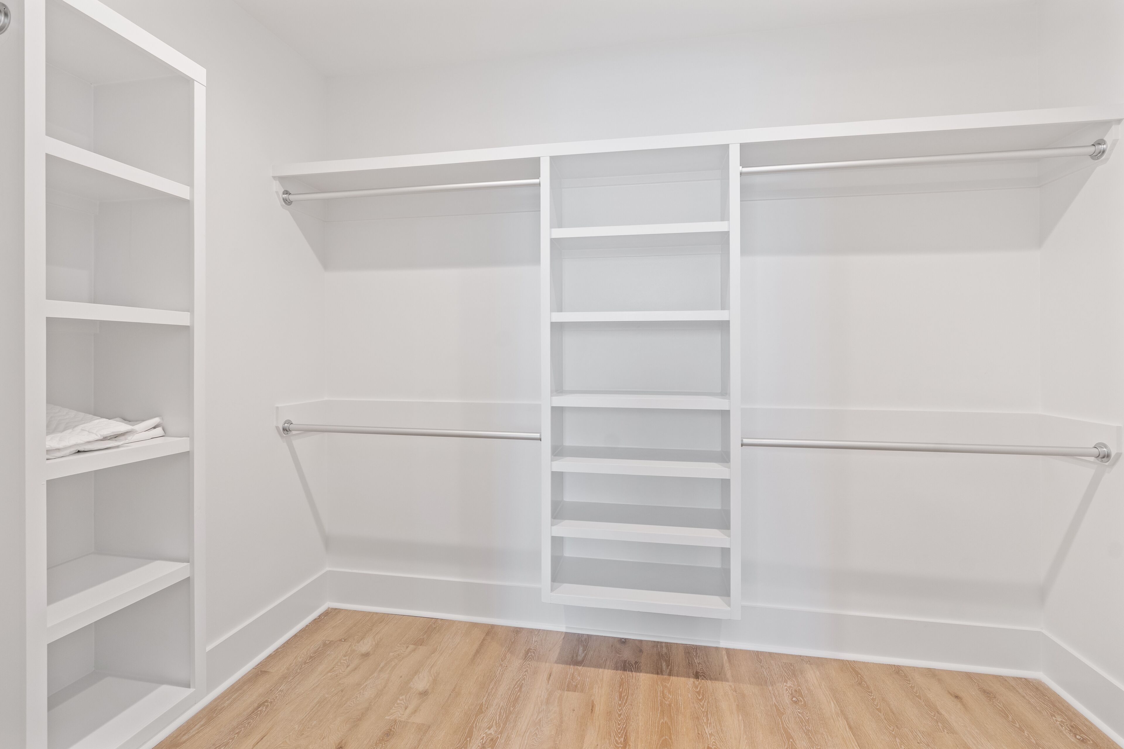 A walk-in closet with open shelving, a hanging rod, and a central ladder.
