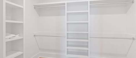 A walk-in closet with open shelving, a hanging rod, and a central ladder.