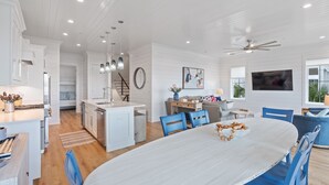 A spacious kitchen with white cabinetry, a central island, and blue chairs around a white dining table.