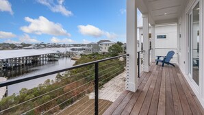 A wooden deck with a blue chair, overlooking a marina with boats and houses.