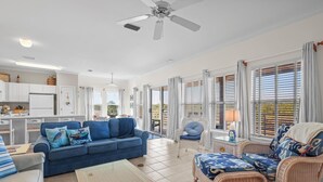 A spacious living area with a blue sofa, wicker chairs, and a dining table.