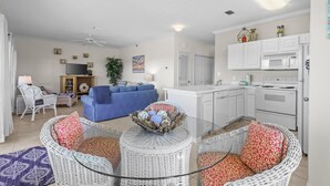 A modern living room with a sofa, wicker chairs, and a glass coffee table.