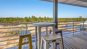 A covered outdoor area with a wooden deck, a round table, and two stools.