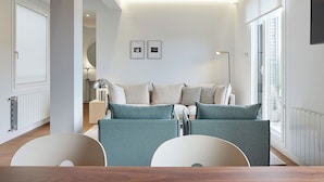 Un salon moderne comprenant un canapé, une table à manger et une grande fenêtre.
