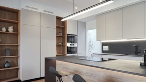 Une cuisine moderne dotée d’un îlot central, de tabourets de bar, de fours encastrés et d’un design minimaliste.