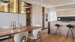 Une cuisine moderne avec une table à manger en bois, des chaises blanches et des tabourets de bar noirs.