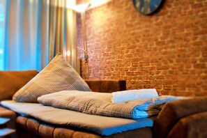 Relax in a cozy room with a rustic brick wall, comfortable sofa, and large window.