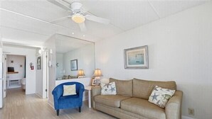 A living room with a beige sofa, a blue armchair, and a ceiling fan.