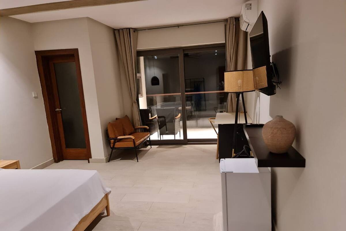 Een hotelkamer met een bed, een stoel, een bureau, een televisie en een groot raam.