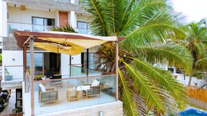 Un hôtel moderne doté d’un balcon en verre, d’un espace extérieur aménagé et d’une piscine.