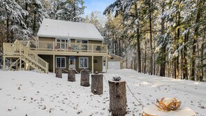 A two-story lodge with a balcony, surrounded by a snowy forest.