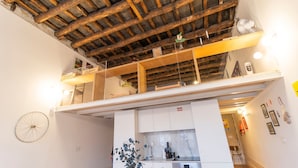 Eine Loft-artige Wohnung mit freiliegenden Holzbalken, einer Küchenzeile und einem Essbereich.