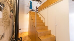 Un escalier en bois avec une main courante, une balustrade en métal et un mur blanc.