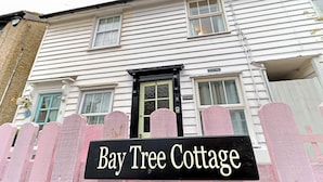Ein zweistöckiges Gebäude mit einem Schild, auf dem 'Bay Tree Cottage' steht.