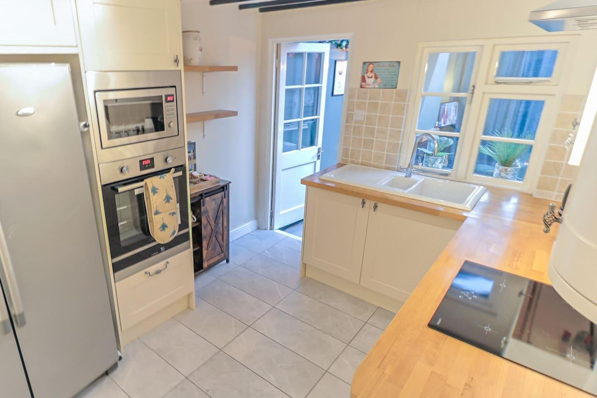 A kitchen with a built-in oven, a microwave, a sink, and a window with a view of the outside.