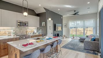 A modern kitchen with a central island, bar stools, and a dining area with a view of the backyard.