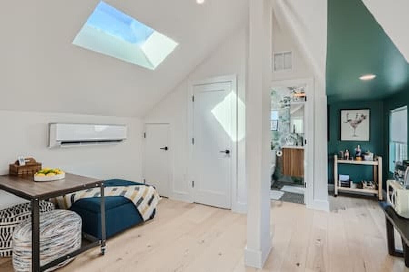 A spacious room with a skylight, a dining area with a table and chairs, and a view into a kitchen area.