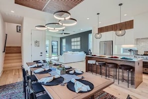 Uma cozinha moderna com ilha central, banquetas e iluminação pendente.