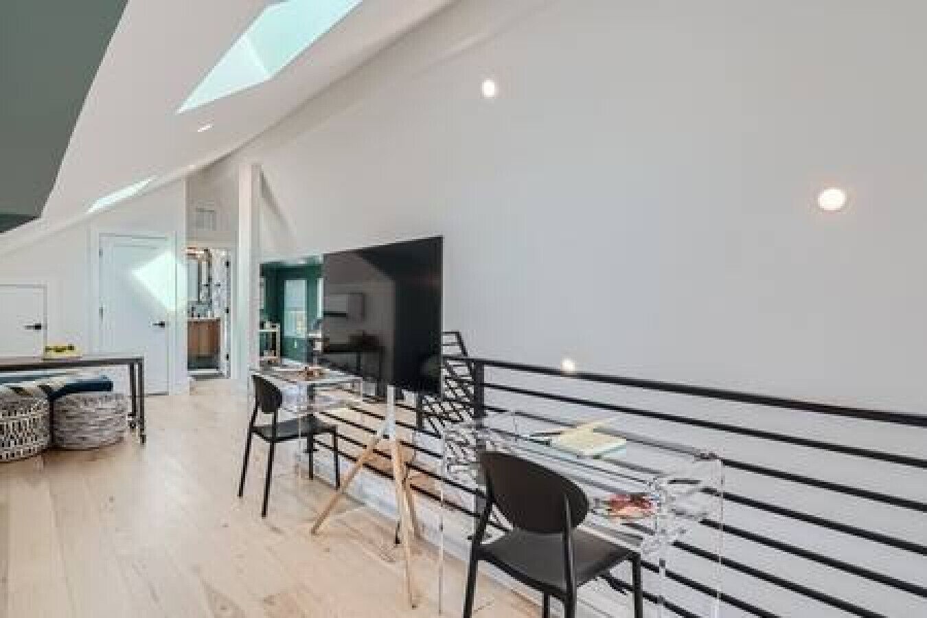 A modern dining area with a long table and chairs, a glass partition, and a view of the kitchen.