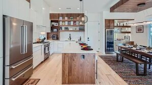 A modern kitchen with a central island, stainless steel appliances, and wooden accents. - Dip into the 512 Experience! 6 BDRMS W/Pool Mins to DT (Austin)