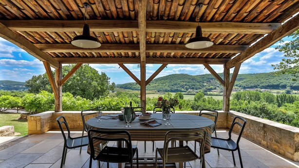 An outdoor patio with a round table and chairs, a wooden pergola, and a scenic view of hills and greenery. - Fully renovated in 2023, a typical house with pool (12x6 m) & spacious garden (Saint-Vincent-de-Cosse)
