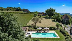 A large rectangular swimming pool with lounge chairs and umbrellas, surrounded by a stone wall and lush greenery. - Fully renovated in 2023, a typical house with pool (12x6 m) & spacious garden (Saint-Vincent-de-Cosse)