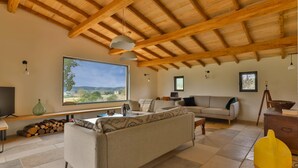 A spacious living room with a large window, wooden ceiling beams, a sofa, a coffee table, and a television. - Fully renovated in 2023, a typical house with pool (12x6 m) & spacious garden (Saint-Vincent-de-Cosse)