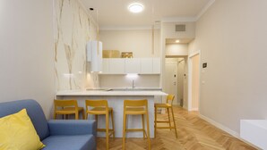 Un salon moderne avec un canapé bleu, un coussin jaune et un parquet en bois disposé en motif chevron.