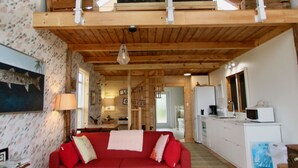 A spacious living room with a red sofa, wooden ceiling beams, and a model ship.