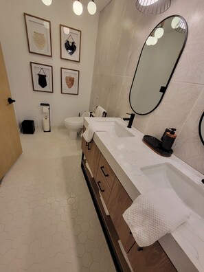 A modern bathroom with a white sink, wooden vanity, and a large mirror.