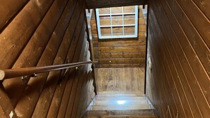 Eine Holztreppe mit Metallgeländer führt zu einem Fenster am oberen Ende.