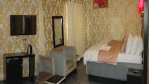 A hotel room with a bed, a TV, a mirror, a small table, and a sofa.