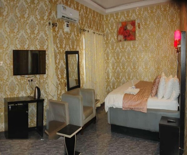A hotel room with a bed, a TV, a mirror, a small table, and a sofa.