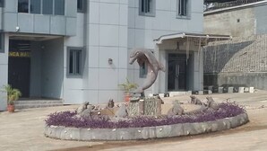 A building with a sign reading "ENGA HALL" and a sculpture of a hand in the center.