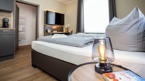 Ett modernt hotellrum med en säng, en sänglampa och en platt-TV.