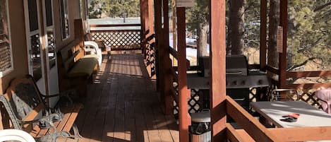 Eine Holzterrasse mit Sitzgelegenheiten im Freien, einem Grill und einem Schild mit den Mietpreisen.