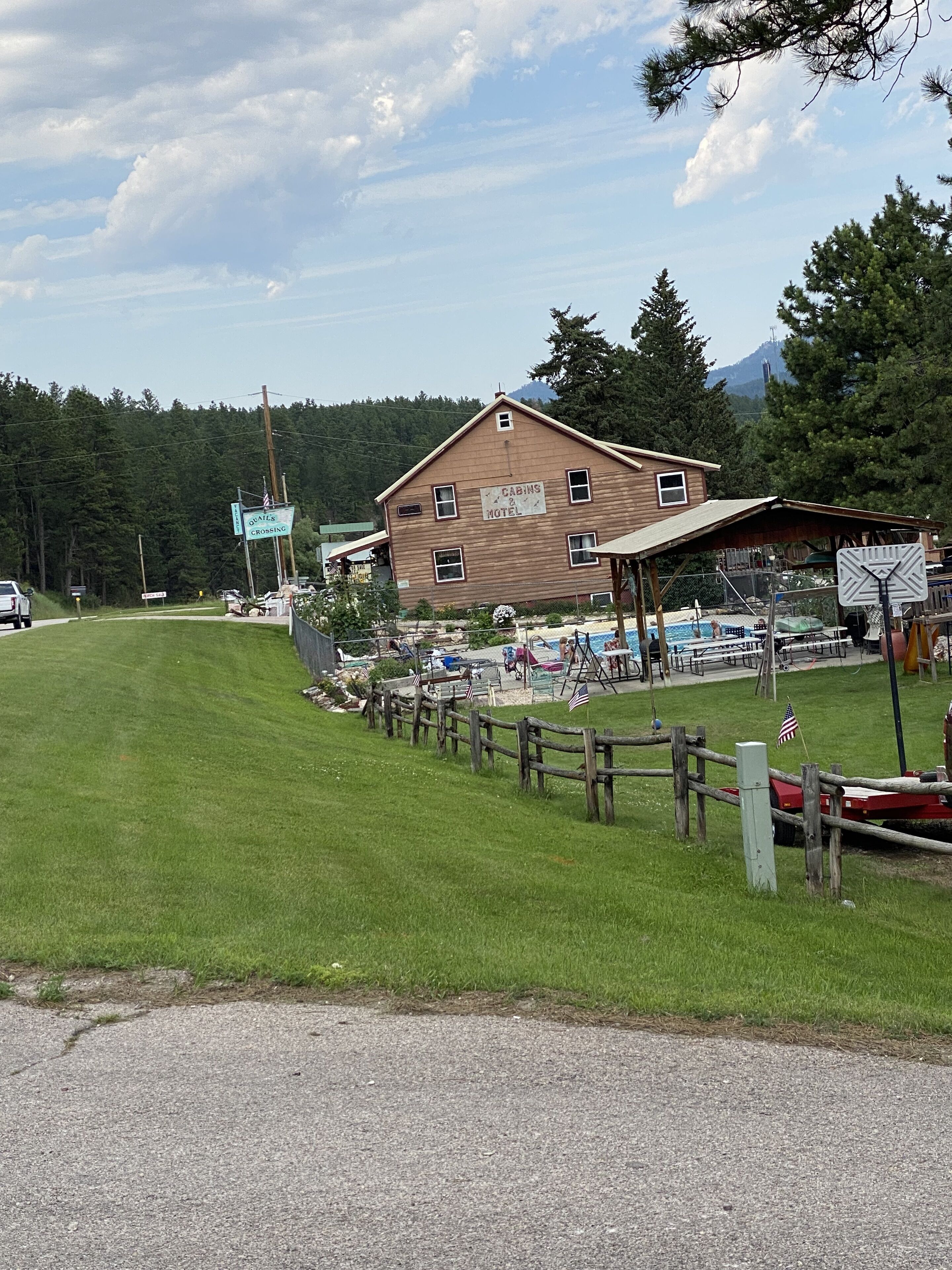 Ein rustikales Holzgebäude, das als Motel ausgeschildert ist, mit einem eingezäunten Außenbereich und einem Pool.