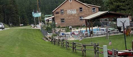 Ein rustikales Holzgebäude, das als Motel ausgeschildert ist, mit einem eingezäunten Außenbereich und einem Pool.