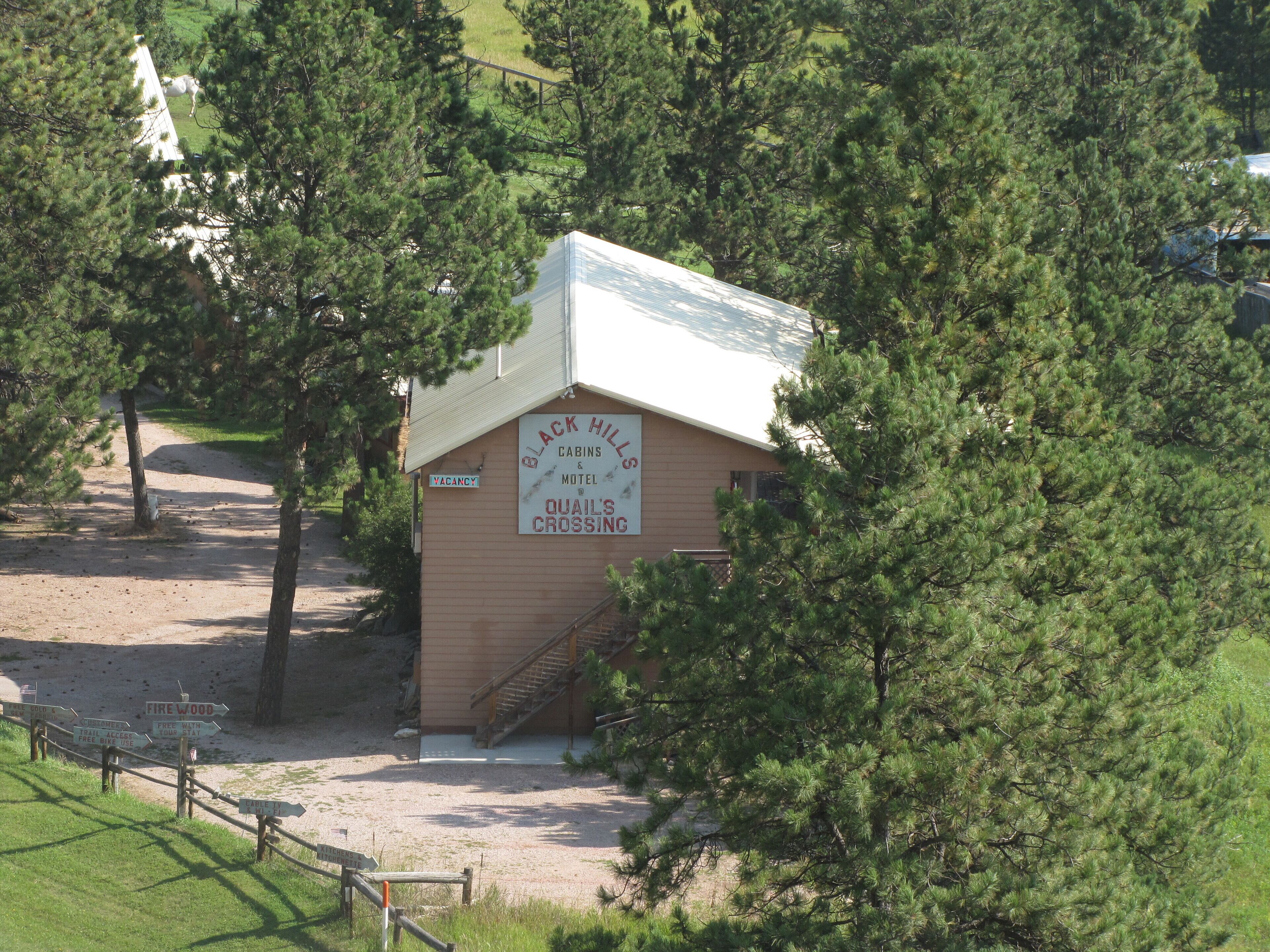 Un petit bâtiment portant l’inscription « Black Hills Cabins & Motel » et sur lequel est affiché un panneau indiquant « Quail’s Crossing ».